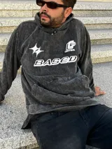 Buzo gris nevado con capucha y bolsillo tipo canguro. Estampado frontal con la palabra "BASED" y un logo.