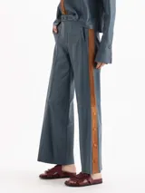 Pantalon sastrero recto confeccionado en cuero ovino color azul, con franjas laterales en color tostado y detalle de botones a lo largo de la pierna.