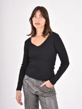 Remera de manga larga en color negro, confeccionada en tejido acanalado con escote en V y delicado detalle de puntilla en el borde.