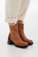 Botas negras de cuero con caña corta, punta cuadrada y cierre lateral con cremallera.