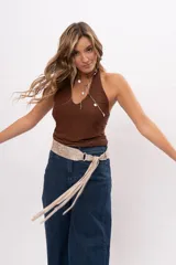 Faja de cuero gamuzado metalizado color visón, con curvatura anatómica, herraje metálico plateado y tiras largas con flecos para atar en nudo.
