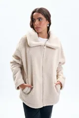 Campera de sherpa color beige, con cuello solapa, cierre frontal completo y bolsillos laterales.