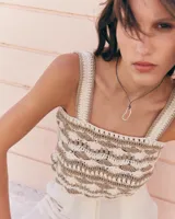 Top tejido a crochet en hilo de algodón color crudo y beige, con breteles anchos y diseño calado.