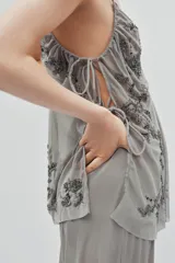 Top de tul con escote en pico y tirantes finos. Presenta bordados florales con aplicación de lentejuelas y laterales ajustables mediante lazadas.