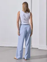 Pantalón de lino estampado a rayas verticales celestes y blancas, marca Zac & Rachel. Tiene pretina con botones, cierre y broche metálico, bolsillos delanteros y bolsillos traseros simulados.