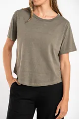 Remera de manga corta con cuello redondo, calce al cuerpo y acabado lavado en tono verde oliva o arena. Presenta un pequeño detalle bordado en forma de estrella cerca del ruedo inferior.