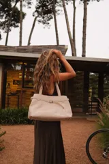 Bolso tote color crema con textura croco, doble asa de hombro y correa extraíble. Interior forrado con bolsillos y llavero.