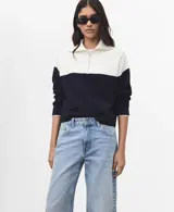 Jersey de punto de manga larga, con diseño bicolor en blanco y negro, cuello alto con cierre de cremallera corta.