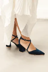 Zapato de taco alto azul oscuro, confeccionado en gamuza, con diseño de punta fina, escote en V y tiras cruzadas en diagonal con hebilla ajustable en el tobillo.