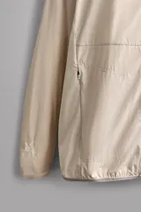 Chaqueta cortavientos de Zara Athleticz color beige, de tejido técnico ligero y elástico, con cuello subido, capucha, cierre frontal de cremallera y bolsillos laterales con cierre oculto.