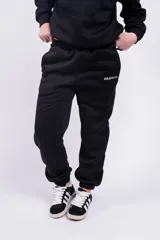 Pantalón de jogging negro con cintura elástica y cordón ajustable. Estampado con la palabra "GRAPHITE" en blanco en la pierna izquierda.