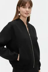 Campera estilo bomber color negro, de manga larga, con cierre frontal y bolsillos.
