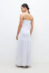 Maxi vestido celeste con rayas verticales blancas y plateadas, breteles finos y corte al bies.