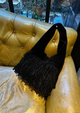 Cartera bandolera negra de gamuza con flecos largos en la parte inferior.
