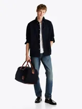 Camisa de sarga de puro algodón teñido en prenda, color azul marino, con cuello abotonado, bolsillo de parche en el pecho, puños redondeados con botón, cinta distintiva en el interior del cuello y logo de Tommy Hilfiger bordado en el bolsillo del pecho.