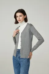 Cárdigan color beige con escote en V y cierre frontal con botones.