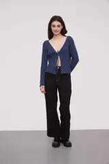 Saco de punto acanalado color azul, con escote profundo en V y cierre frontal mediante lazo para anudar. Presenta mangas largas y diseño holgado.