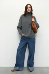 Polera gris de tejido de punto, corte oversized, cuello alto y mangas largas.