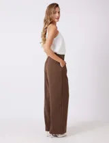 Pantalón palazzo de tiro alto en color verde militar, con diseño de doble abotonadura frontal, pinzas en la cintura y pierna ancha. Cuenta con cintura elástica en la parte posterior para mayor ajuste y bolsillos laterales funcionales.