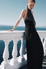 Top de cuello halter con hombros descubiertos, confeccionado con una combinación de tejidos. La parte superior presenta un estampado de lunares, mientras que la parte inferior es de tejido liso acanalado.