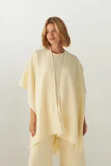 Ruana de diseño abierto, confeccionada en lana fina sin teñir, con terminaciones artesanales en crochet.