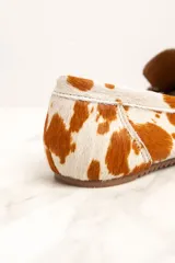 Mocasines de cuero con animal print de vaca en tonos blanco y marrón.