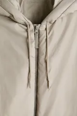 Campera acolchada de tejido funcional repelente al agua y rompevientos, color gris claro, de corte holgado con capucha ajustable, cierre frontal, bolsillos delanteros y puños elastizados.