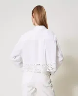 Camisa blanca de popelina de algodón con corte boxy y encaje macramé en el bajo. Presenta cuello clásico, manga larga con sisa caída, puños con abertura y botones, cierre con botones, bolsillos aplicados en la parte delantera y placa con logotipo Oval T en la parte trasera.