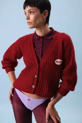 Cardigan marrón de punto grueso con cuello en V, cierre frontal con botones y parche bordado en el pecho.