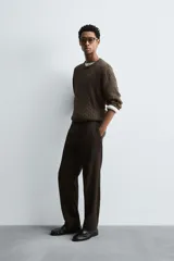 Jersey de punto color marrón oscuro, con cuello redondo y manga larga. Presenta un tejido con estructura de ochos y acabados en rib.