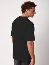 Remera holgada de algodón color beige con lavado ácido, cuello redondo ancho y diseño de tres pequeños círculos estampados en el pecho.