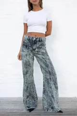 Jean de mujer de corte acampanado, tiro alto, color gris con efecto acid wash. Presenta costuras verticales en la parte delantera y bolsillos de parche.