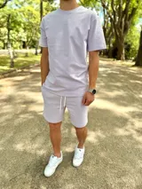 Conjunto deportivo compuesto por una remera de manga corta y un short lila con cordón de ajuste blanco.