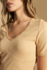 Remera de manga corta en tejido acanalado, con escote en V y detalles de puntilla en el borde del escote y en las mangas. Presenta un ajuste entallado al cuerpo.