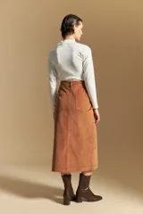 Falda midi de pana color marrón, con tiro alto, abotonadura frontal completa y bolsillos aplicados en el frente.