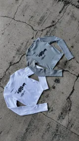 Remera blanca de manga larga y corte ajustado, confeccionada en tejido rib con diseño estampado en el frente.