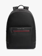 Mochila Tommy Hilfiger de color negro, confeccionada en poliuretano con paneles de texturas mixtas y diseño curvo. Cuenta con un compartimento principal con cremallera de doble cierre, funda interior para portátil, bolsillo interior con cremallera y un bolsillo exterior frontal con cierre y detalles en rojo y azul marino. Incorpora asa superior, correas ajustables y acolchadas, respaldo con panel de malla acolchado y logo metálico de la marca en la parte delantera.