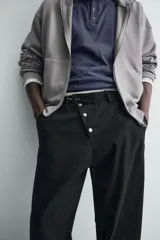 Pantalón wide fit de algodón con efecto lavado, corte recto y holgado. Presenta un cierre frontal cruzado con botones y un alamar metálico distintivo, además de bolsillos frontales y traseros de plastrón.