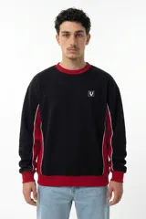 Buzo de corte oversize con diseño colorblock en negro y rojo. Presenta cuello redondo, puños y cintura acanalados, y paneles laterales con vivos blancos. Incluye logo bordado en el pecho.
