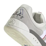 Championes adidas Adimatic de estilo skate, con diseño robusto en tonos gris y blanco. Presenta las icónicas tres tiras laterales con detalles en rojo y azul, suela de goma con patrón geométrico y cordones anchos.