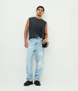 Pantalón baggy de jean celeste con diseño estampado de grafitis en estilo lettering blanco. Cuenta con cintura con trabillas, cierre frontal de botón y cremallera, y bolsillos clásicos.