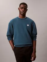 Buzo Calvin Klein de cuello redondo, color azul, confeccionado en algodón terry, con puños y dobladillo de punto canalé y parche con mini monograma de la marca en el pecho.