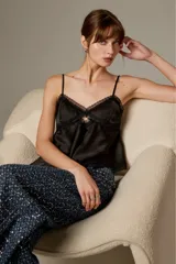Musculosa de satén color blanco, con breteles finos regulables, escote en V decorado con detalles de encaje y diseño fluido.