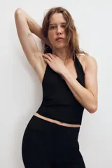 Top de punto color beige, con cuello halter y escote redondo pronunciado, de diseño ajustado al cuerpo.