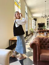 Bolso tipo tote bag negro de cuero, con costuras a la vista y manijas cortas.