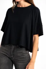 Remera de corte oversize, confeccionada en tejido de viscosa con textura acanalada, de color negro, con mangas cortas y cuello redondo.