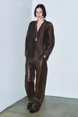 Pantalón de tiro medio, pierna recta, confeccionado en tejido efecto piel marrón oscuro con acabado arrugado. Presenta cinco bolsillos y cierre frontal con cremallera y botón.
