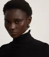 Blusa de punto de manga larga con cuello alto, diseño ajustado al cuerpo y tejido de textura suave.