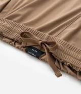 Pantalón deportivo de corte recto, color marrón, con cintura elástica y cordón de ajuste. Presenta bolsillos laterales con cierre y un diseño minimalista de tejido técnico.