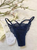 Pack de tres tangas de encaje con diseño de tiras laterales regulables. El conjunto incluye una pieza en color azul marino, una en color blanco y una en color champagne.